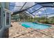 Beautiful screened-in pool area with brick pavers, clear blue pool water, and patio seating at 7175 Bottle Brush Dr, Spring Hill, FL 34606