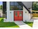 A-frame home's front entrance, highlighting modern design, black trim, and vibrant red double doors at 7422 New York Ave, Hudson, FL 34667