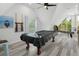 A pool table is covered in a game room with grey wood-look floors and ample light at 7422 New York Ave, Hudson, FL 34667