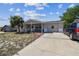 Cozy one-story home featuring a covered front porch, long driveway, and mature trees at 7535 Christina Ln, Port Richey, FL 34668