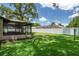 A well-manicured lawn in the backyard includes a screened in porch and a white vinyl fence for privacy at 7630 Landmark Dr, Spring Hill, FL 34606