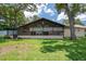 The backyard of the home has a covered porch and a mature tree providing shade to the lawn at 7630 Landmark Dr, Spring Hill, FL 34606