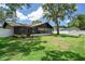 A sunny backyard with lush grass, mature trees, a storage shed, and a screened in porch at 7630 Landmark Dr, Spring Hill, FL 34606