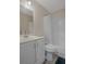 A well-lit bathroom featuring a vanity, toilet, and shower-tub combination with a white shower curtain at 7630 Landmark Dr, Spring Hill, FL 34606
