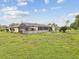 A wide view of the backyard with a screened in patio, lush grass and mature landscaping at 8393 Delaware Dr, Weeki Wachee, FL 34607