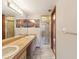 Bathroom featuring double sinks, wood-look cabinets, large mirror, and walk-in shower with glass door at 8393 Delaware Dr, Weeki Wachee, FL 34607