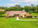 Beautiful single-story home featuring a manicured lawn, mature trees, and a welcoming walkway to the front door at 8393 Delaware Dr, Weeki Wachee, FL 34607