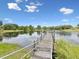 Picturesque lake view showcasing a wooden dock extending into calm waters with lush vegetation around the shoreline at 8393 Delaware Dr, Weeki Wachee, FL 34607