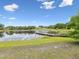 Beautiful lake view with a wooden dock and the blue sky reflecting on the water near the grassy shoreline at 8393 Delaware Dr, Weeki Wachee, FL 34607