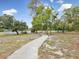 A picturesque walking path leads to a tennis court surrounded by mature trees at 8393 Delaware Dr, Weeki Wachee, FL 34607