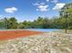Well-maintained tennis court featuring a textured surface, surrounded by lush greenery at 8393 Delaware Dr, Weeki Wachee, FL 34607