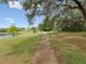 Scenic walking path next to a lake surrounded by lush greenery and trees under a bright sky at 8393 Delaware Dr, Weeki Wachee, FL 34607