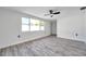 A bedroom filled with bright, natural light, and light grey wood floors and a ceiling fan at 9005 Lido Ln, Port Richey, FL 34668