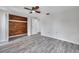 Well-lit bedroom with wood-look flooring, ceiling fan, and a closet with wooden accents and shelving at 9005 Lido Ln, Port Richey, FL 34668