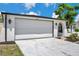 Two-car garage of single-story home with white door, black trim, and manicured landscaping at 9005 Lido Ln, Port Richey, FL 34668