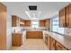 Well-lit kitchen featuring tile flooring, wood cabinets, white appliances, and an overhead skylight at 9005 Lido Ln, Port Richey, FL 34668