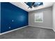 An unfurnished bedroom featuring a blue accent wall, grey carpet and a ceiling fan at 9251 Geneva St, Spring Hill, FL 34608
