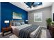 A furnished bedroom with a blue accent wall, ceiling fan, and a grey bed at 9251 Geneva St, Spring Hill, FL 34608