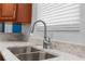 Close up of a stainless steel double sink in a kitchen with cherry wood cabinets and granite countertops at 9251 Geneva St, Spring Hill, FL 34608