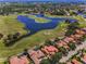 Scenic aerial view of a golf course community with a lake, lush greenery, and beautiful homes with red tile roofs at 9933 Milano Dr, Trinity, FL 34655
