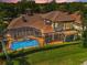 Aerial view of home with screened-in pool, balcony, and lush green lawn at 9933 Milano Dr, Trinity, FL 34655