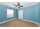 Cozy bedroom featuring blue walls, a ceiling fan, and a closet, perfect for a relaxing retreat at 9933 Milano Dr, Trinity, FL 34655