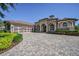 Elegant home featuring a paver driveway, manicured landscaping, and a three-car garage at 9933 Milano Dr, Trinity, FL 34655