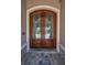 Close up of a decorative wooden front door with glass panels and stone trim at 9933 Milano Dr, Trinity, FL 34655