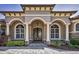 Elegant stucco home exterior featuring arched windows, stone accents, and a covered entryway at 9933 Milano Dr, Trinity, FL 34655