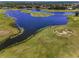 Aerial view of a golf course with a scenic lake and manicured green fairways at 9933 Milano Dr, Trinity, FL 34655