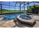 Screened pool with an attached hot tub overlooking a scenic golf course and pond at 9933 Milano Dr, Trinity, FL 34655