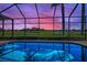 Relaxing screened-in pool overlooking a lush golf course and pond at 9933 Milano Dr, Trinity, FL 34655