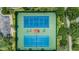 Aerial view of tennis courts with blue and green surfaces, surrounded by lush greenery and a parking lot at 9933 Milano Dr, Trinity, FL 34655