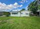 This backyard view shows the home's exterior and a green lawn with chainlink fencing for added security at 10014 Kingswood Ln, Port Richey, FL 34668