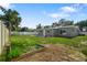View of backyard showing planted garden and a grey house with white trim surrounded by a white fence at 1004 Peninsula Ave, Tarpon Springs, FL 34689