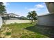 Spacious backyard with lush grass, a privacy fence, and views of neighboring homes with screened enclosures at 1004 Peninsula Ave, Tarpon Springs, FL 34689