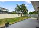 View of backyard with grassy lawn and a concrete patio leading to the home, landscaped with palm trees at 1004 Peninsula Ave, Tarpon Springs, FL 34689