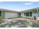 View of the single-story home showing the 2-car garage, front door, and landscaped entry at 1004 Peninsula Ave, Tarpon Springs, FL 34689