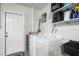Clean laundry room with modern washer and dryer, shelving, and access door, providing convenience and functionality at 1004 Peninsula Ave, Tarpon Springs, FL 34689