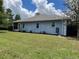 View of the backyard with a spacious lawn, garden bed and blue exterior walls at 10054 Hernando Ridge Rd, Weeki Wachee, FL 34613