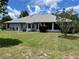 View of the backyard with a spacious lawn, screened in porch, and lush greenery at 10054 Hernando Ridge Rd, Weeki Wachee, FL 34613