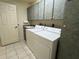 Well-equipped laundry room with upper cabinets, sink, and modern appliances, including a washer and dryer at 10054 Hernando Ridge Rd, Weeki Wachee, FL 34613