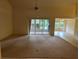 Spacious living room with neutral carpet, sliding glass doors to the porch, and view to other areas of the home at 10054 Hernando Ridge Rd, Weeki Wachee, FL 34613