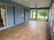 A sunroom with a blue textured wall with many windows and laminate wood flooring at 10054 Hernando Ridge Rd, Weeki Wachee, FL 34613