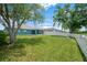 Large backyard with a white fence, mature trees, and a screened-in pool enclosure in the distance at 1009 Summer Breeze Dr, Brandon, FL 33511
