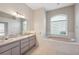 Bathroom featuring double sinks, a large soaking tub, and a window at 10296 Palmgren, Spring Hill, FL 34608