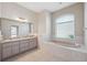 Bathroom featuring double sinks, a large soaking tub, and a window at 10296 Palmgren, Spring Hill, FL 34608