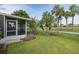 Lovely, lush backyard featuring mature palms and landscaping along the exterior of the screened lanai at 1105 Flora Vista St, New Port Richey, FL 34655