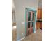 Unique pantry with a turquoise and pink painted door and bronze accents creates a focal point in the kitchen at 11055 Belle Haven Dr, New Port Richey, FL 34654