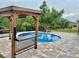 Backyard featuring a fenced pool with a bar, a wooden pergola, and professional landscaping at 11055 Belle Haven Dr, New Port Richey, FL 34654